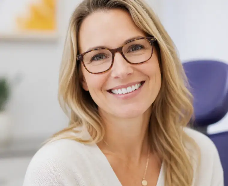 Smiling patient wearing new tortoiseshell glasses in the exam lounge